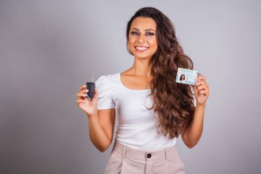 Brezilyalı bir kadın, kahverengi saçlı, ehliyeti var, Brezilya belgesi ve araba anahtarı, yeni araba..