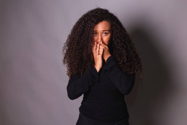 Kadın cinayeti bilinci lehine konuşan Afro kadın. Aile içi şiddet. Eller ağızda, sessizlik..