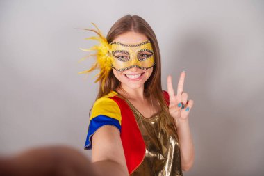 Brezilyalı sarışın kadın, frevo kıyafetler giymiş, karnaval maskesi takmış, selfie çekiyor..
