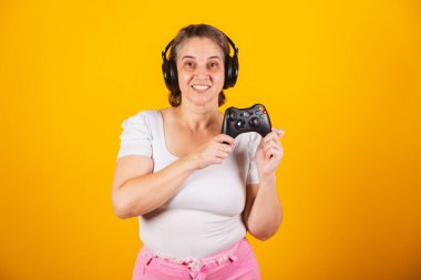 Yetişkin Brezilyalı kadın, anne, video oyunu kumandası, joystick. Oyuncu. Kulaklık takmak, internetten çalmak..