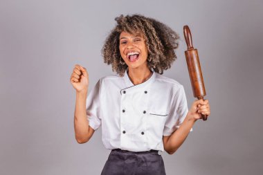 Genç siyah Brezilyalı kadın, aşçı, şef, restoran üniforması giyiyor. Elinde makarna, ekmek ve pizza hazırlamak için tahta raptiye vardı..