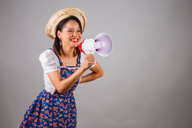 Brezilyalı kadın, kuzeydoğuda, Haziran partisi kıyafetleriyle, hasır şapkalı. Reklam, reklam ve pazarlama için mega telefon kullanmak..