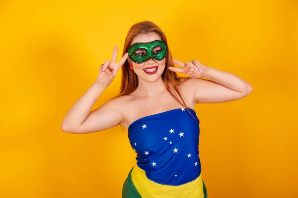 ブラジルの国旗で作られたカーニバルの服を着た美しいブラジルの赤毛の女の子平和と愛のサインを作る — ストック写真