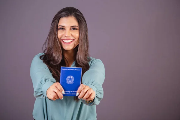 Horizontal photo. Beautiful Brazilian woman, with casual clothes, Jeans and green shirt. holding work card and social security. Document.