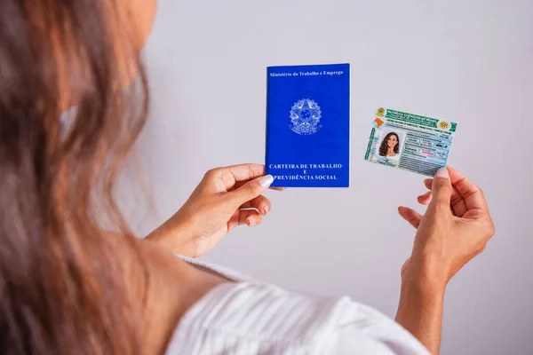 Hand holding driver\'s license and work and social security card, brazilian documents.