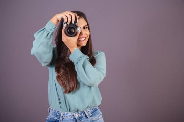 Yatay fotoğraf. Güzel Brezilyalı kadın, günlük kıyafetler, kot pantolon ve yeşil gömlekli. Kadın fotoğrafçı fotoğraf makinesi tutuyor..