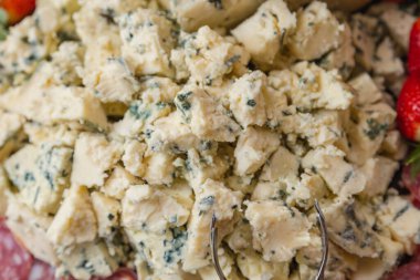 Gorgonzola peyniri, bir şarküteri tahtasında, çilek ve salamın yanında..