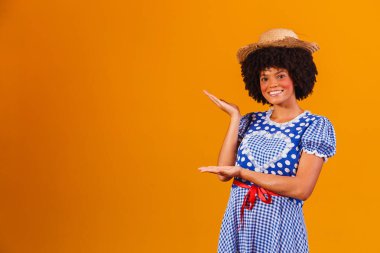 Festa Junina için tipik kıyafetler giyen Brezilyalı afro kadın sarı arka planda