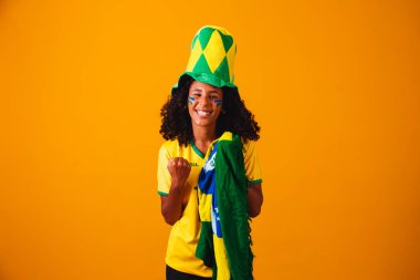 Brezilyalı bir hayran. Brezilyalı taraftar sarı arka planda futbol ya da futbol maçını kutluyor. Brezilya 'nın Renkleri.