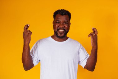 Sarı arka planda parmakları çapraz olan afro adam.