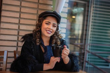 Kışın fırında kahve ya da sıcak çikolata içen Afro bir kadın..