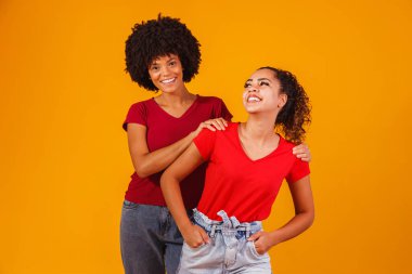 Genç, güzel ve mutlu afro kadın arkadaşlar kameraya gülümsüyor..