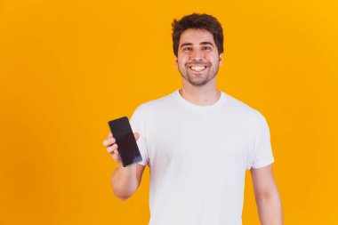 Elinde cep telefonu olan yakışıklı adam mesaj için yeri işaret ediyor.