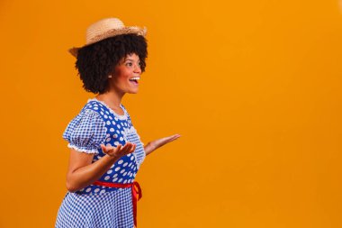 Festa Junina için tipik kıyafetler giyen Brezilyalı afro kadın sarı arka planda