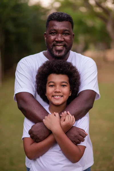 黒の父と息子で公園でお互いの笑顔を保持カメラを見て — ストック写真