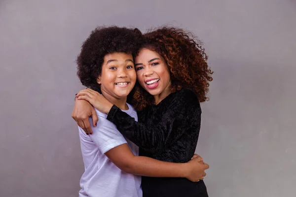 black mother and son hugging on gray background