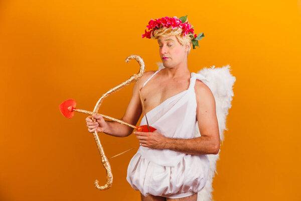 Valentine's day concept. Portrait of the God of love - Cupid with bow and arrow on a yellow background.