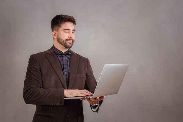 灰色の背景でノートパソコンを操作するハンサムな男 — ストック写真