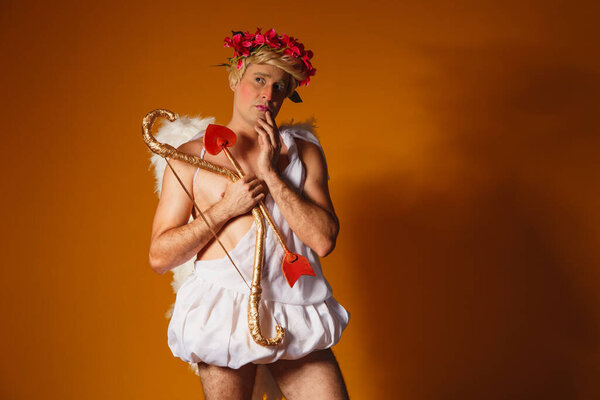 Valentine's day concept. Portrait of the God of love - Cupid with bow and arrow on a yellow background.
