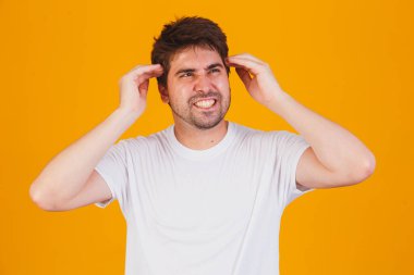 Stresten dolayı eli başının üstünde beyaz tişört giyen yakışıklı bir genç adam. Migren ağrısı..