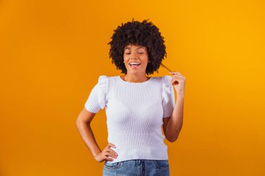 Afro saç stili ve cazibeli makyajlı Afro-Amerikan kadının güzel portresi. Brezilyalı kadın. Karışık ırk. Kıvırcık saçlı. Saç stili. Sarı arkaplan
