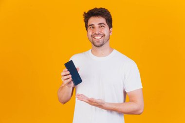 Elinde cep telefonu olan yakışıklı adam mesaj için yeri işaret ediyor.