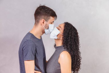 Yeni nesil koruyucu maskeler takan ve birbirlerini öpen genç çiftler, virüs önleme ve insan konsepti yaydılar. Maskeli sevgililer günü çifti. Karantina