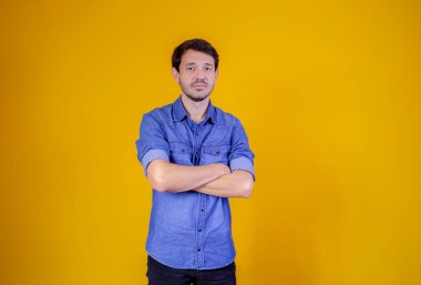 Sarı arka planda kolları çaprazlanmış yakışıklı bir adam..