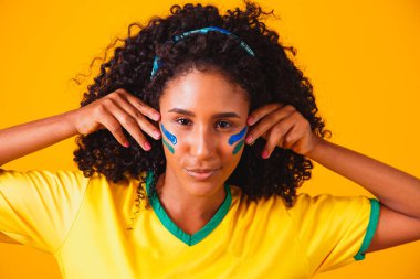 Brezilyalı bir hayran. Brezilya taraftarı, sarı arka planda futbolu ya da futbol maçını kutluyor. Brezilya 'nın Renkleri.