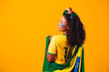 Brezilyalı bir hayran. Portrede Brezilya bayrağı takan Brezilyalı bir taraftar futbol ya da futbol maçını sarı arka planda kutluyor. Brezilya Renkleri. Dünya Kupası.