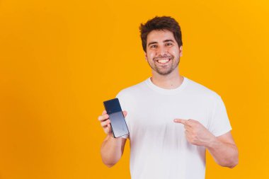 Elinde cep telefonu olan yakışıklı adam mesaj için yeri işaret ediyor.