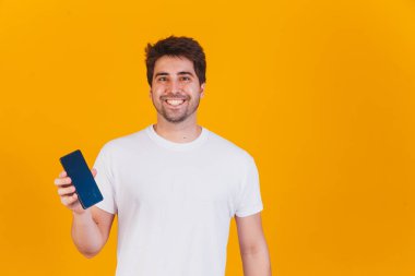 Elinde cep telefonu olan yakışıklı adam mesaj için yeri işaret ediyor.