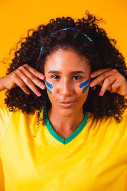 Brezilyalı bir hayran. Brezilya taraftarı, sarı arka planda futbolu ya da futbol maçını kutluyor. Brezilya 'nın Renkleri.