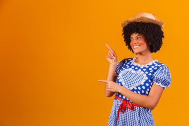 Festa Junina için tipik kıyafetler giyen Brezilyalı afro kadın sarı arka planda