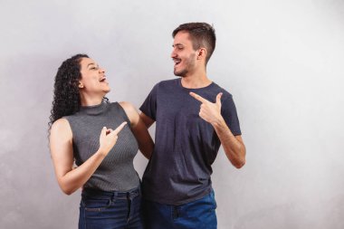 Gri arka plandaki genç çift işaret ediyor. Metin için boşluk