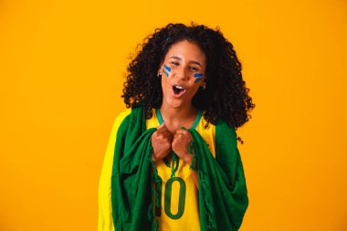 Brezilyalı bir hayran. Portrede Brezilya bayrağı takan Brezilyalı bir taraftar futbol ya da futbol maçını sarı arka planda kutluyor. Brezilya Renkleri. Dünya Kupası.