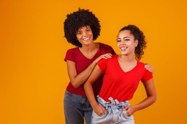 Genç, güzel ve mutlu afro kadın arkadaşlar kameraya gülümsüyor..