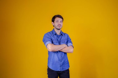 Sarı arka planda kolları çaprazlanmış yakışıklı bir adam..