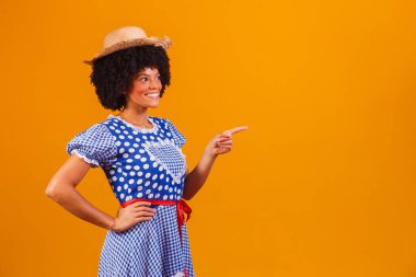 Festa Junina için tipik kıyafetler giyen Brezilyalı afro kadın sarı arka planda