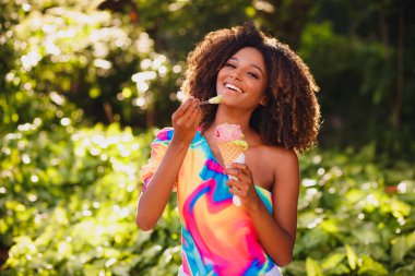 Parkta dondurma yiyen mutlu afro kadın..