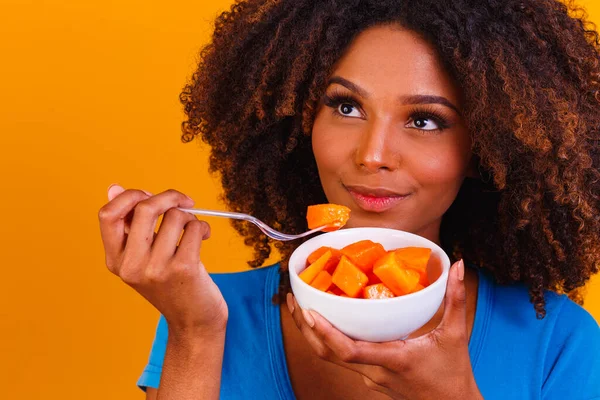 afro girl eating papaya from the bowl. Healthy eating concept