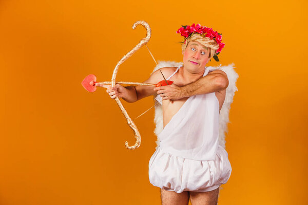 Valentine's day concept. Portrait of the God of love - Cupid with bow and arrow on a yellow background.