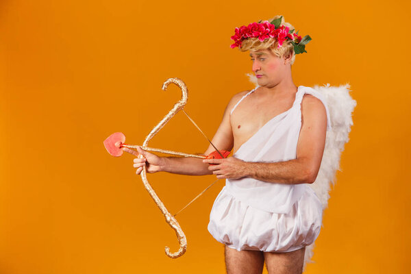 Valentine's day concept. Portrait of the God of love - Cupid with bow and arrow on a yellow background.