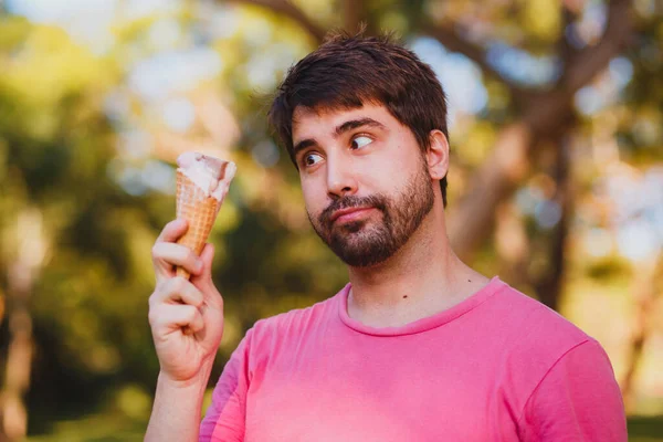 公園でアイスクリームを食べる若いハンサムな男 — ストック写真