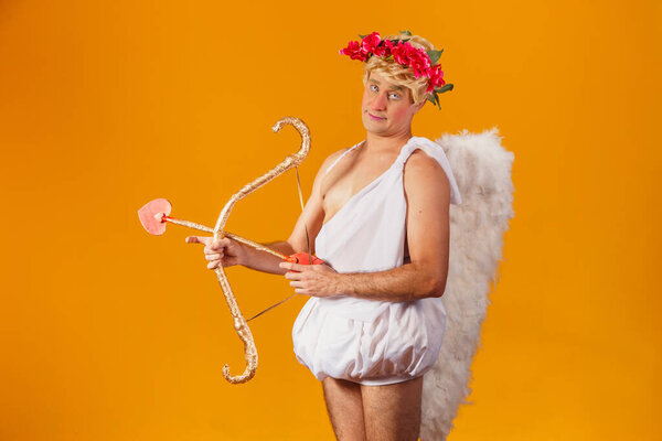 Valentine's day concept. Portrait of the God of love - Cupid with bow and arrow on a yellow background.