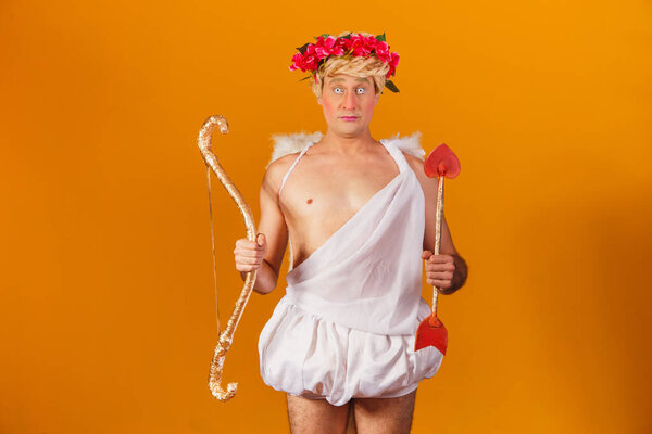 Valentine's day concept. Portrait of the God of love - Cupid with bow and arrow on a yellow background.