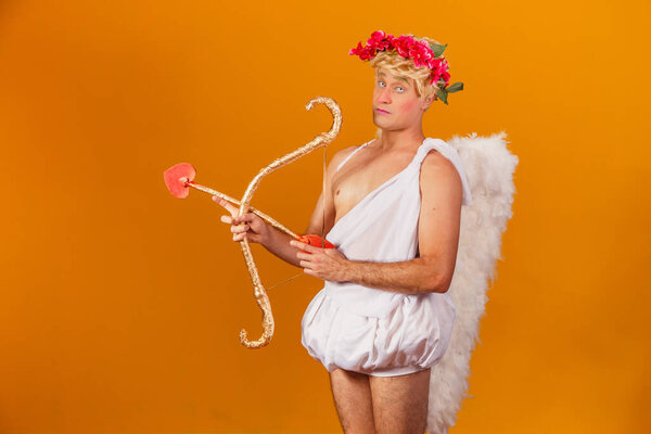 Valentine's day concept. Portrait of the God of love - Cupid with bow and arrow on a yellow background.