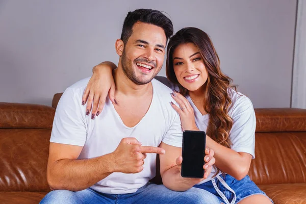 Valentine couple holding a smartphone with the screen with space for text.