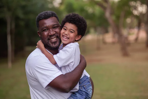 父亲和非洲裔儿子在公园里互相抱抱着 父亲节 — 图库照片