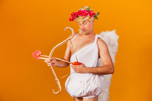 Valentine's day concept. Portrait of the God of love - Cupid with bow and arrow on a yellow background.